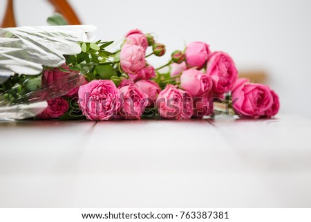 Photo of bouquet of pink peonies on white wooden table