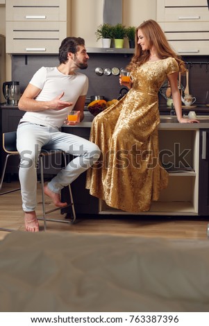 Picture of loving couple in kitchen with glasses with juice in morning