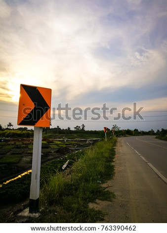 The evening time traffic sign placed beside along on the road.