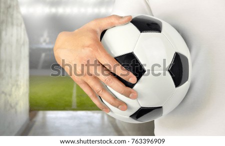 Cropped image of a young man holding a soccer ball with his hand wearing white tshirt  at Madrid and copy space at football stadium