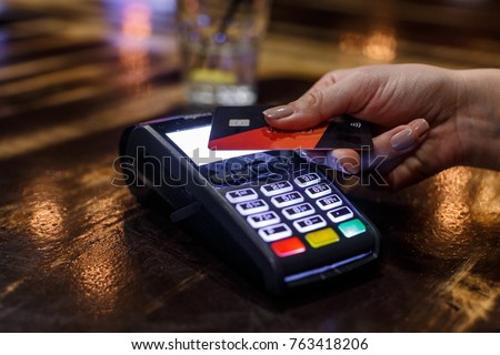 Non-cash transaction - Credit card payment in a bar. Close up photo of woman hand paying with credit card. Royalty-Free Stock Photo #763418206