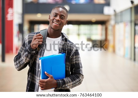 Portrait Of Male Student Standing In College Building Royalty-Free Stock Photo #763464100