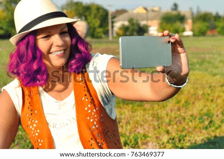 Beautiful stylish young hipster woman with pink curly hair enjoying day, taking selfie. Young cute positive woman having recreation using technology 