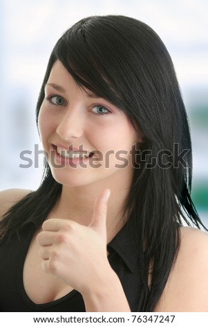 Portrait of attractive young woman showing a thumbs up on blue background