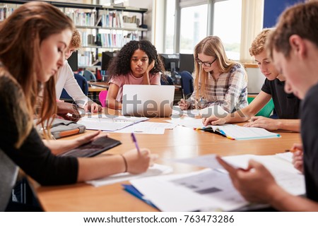 Group Of College Students Working Around Table In Library