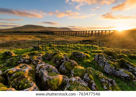 Gorgeous golden light as the sun sets behind the Ribblehead Viaduct with rocks in foreground. Royalty-Free Stock Photo #763477546