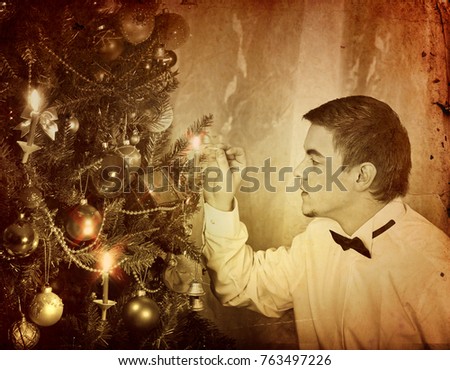 Man alone put up Christmas tree. Expectation of holiday on eve of Xmas party at home alone. Black and white Xmas vintage image.