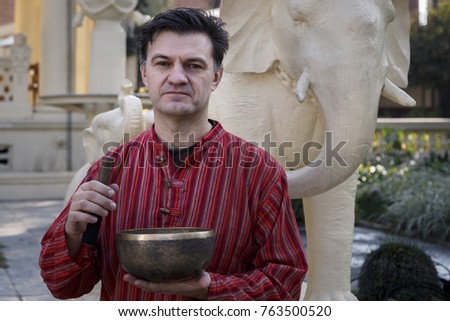 The man is holding a Tibetan singing bowl. Sound therapy. The man in the red shirt.