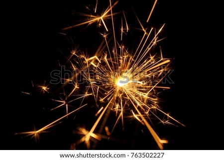 Burning Bengal fire on a black background. Christmas, New Year sparkle fire. Festive background, bengal light on the dark background. Fireworks