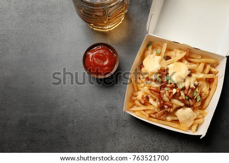 Cardboard box with french fries, cheese and bacon on grey background