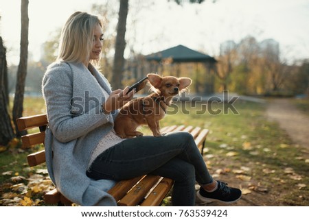 young beautiful Woman in the park with her funny long-haired chihuahua dog. Autumn background 
