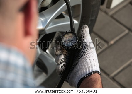 Man checking tyre pressure on a car wheel