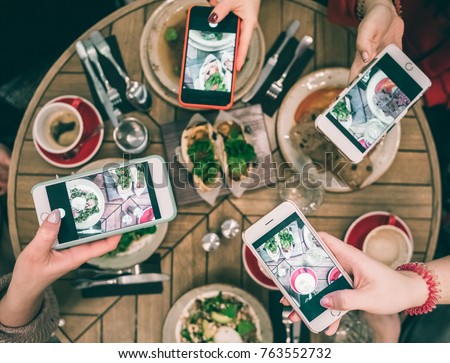 Group of food bloggers taking photo of dishes in the restaurant table. Top view. Friends lunch, social media funs Royalty-Free Stock Photo #763552732