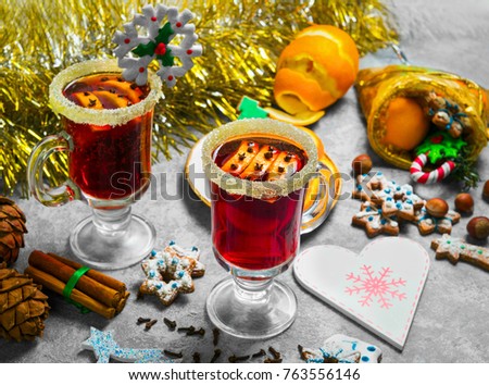 New Year's drink mulled wine with Christmas cookies. New Year's tinsel on the table, ingredients for mulled wine oranges, spices, nuts. On the glass with drink mulled wine is Christmas snowflake. 