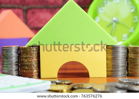 Housing loan conceptual photo using toy house, isolated on brick background. In relation with loan, coins, time value of money concept. Selective focused.