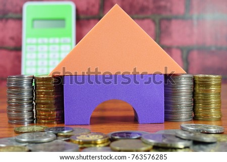Housing loan conceptual photo using toy house, isolated on brick background. In relation with loan, coins, time value of money concept. Selective focused.