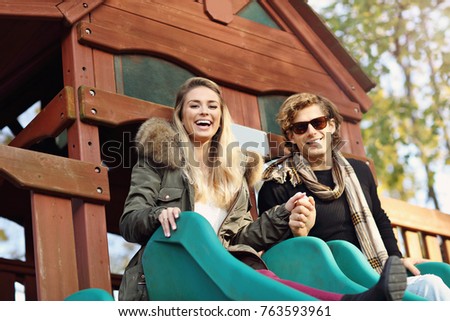 Picture showing joyful couple having fun at sliding board outdoors
