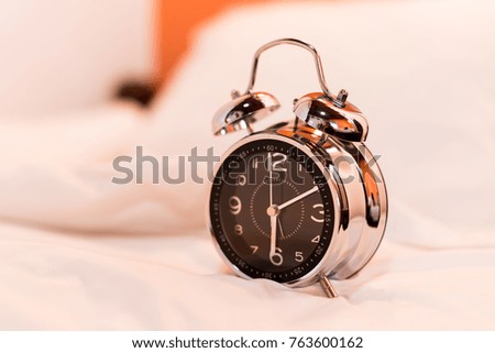 Close up black and silver alarm clock on bed in the bedroom.