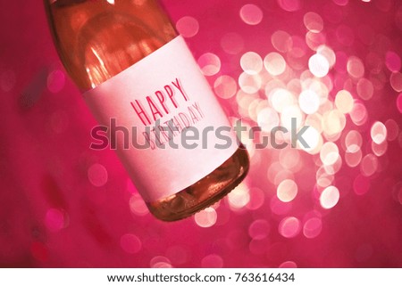 Champagne or win with text Happy birthday. Happy birthday party background. Happy birthday greeting card. Birthday party. Celebration. Champagne bottle with colorful party streamers on pink