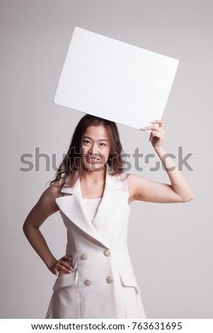 Young Asian woman with white blank sign on gray background