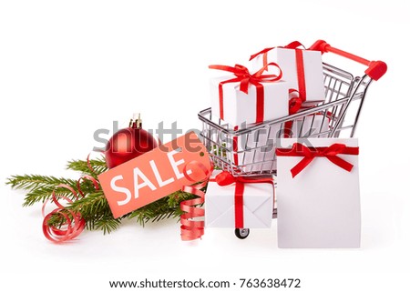 Shopping trolley with white gift boxes and brenches of fir-tree with decoration on a white background. Christmas and New Year sale.