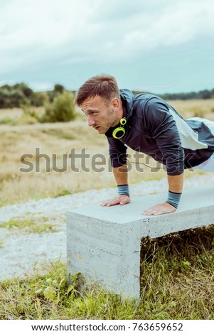 Handsome young athlete is doing push ups
