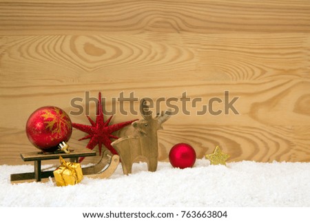 Christmas background with wood deer and red ball on sledge.