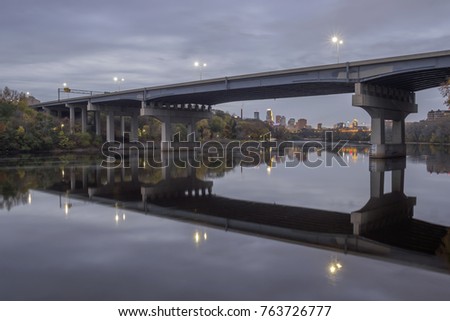 A Wide Angle Shot of the Dartmouth Bridge over the Mississippi River with Downtown Minneapolis in the Background Reflecting in the Smooth Mississippi River during a Cloudy Fall Dusk