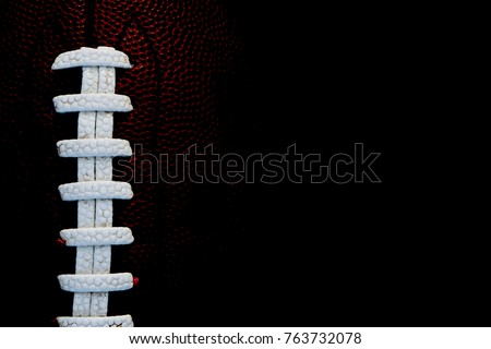 American Football on black background with white leather laces and space for text about sport