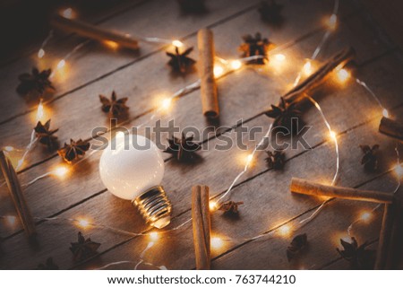 Holidays illuminations and cinnamon with star anise around on wooden background. Image in old color style