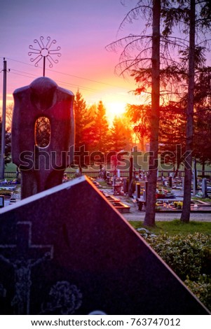 tombstones and silhouettes of crosses and trees against sky at sunset in an old Christian cemetery