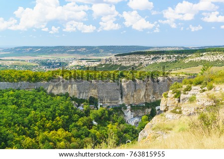 Landscape view on the natural boundary of Mariam-Dere (Canyon of Maria), Holy assumption Orthodox cave monastery and the town of Bakhchisaray on the horizon. Crimea