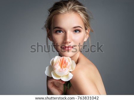 Beautiful girl with beautiful makeup. Photo of blonde girl with rose on grey background. Youth and skin care concept