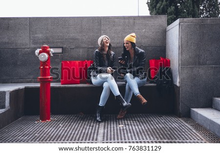 Two friends with smartphone in shopping street