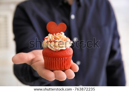 Man holding tasty cupcake for Valentine's Day