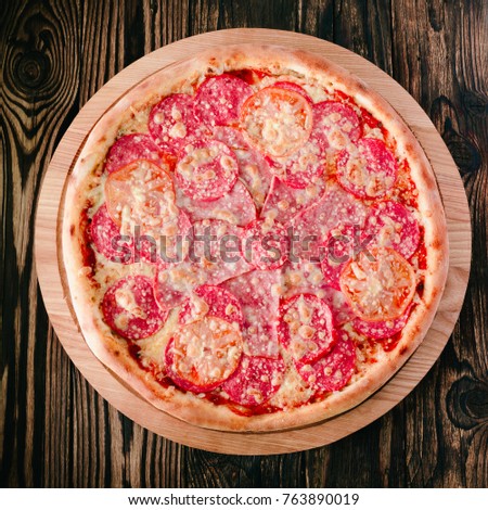 cooked pizza on a round cutting board and a wooden background