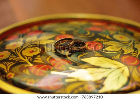 wedding rings closeup on the tray. Russian folk pattern