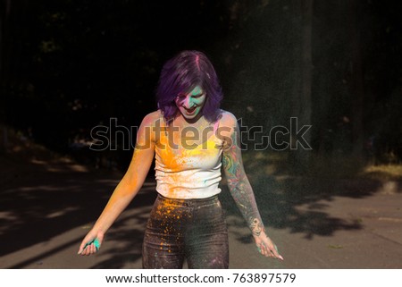 Laughing tattooed young woman covered with dry powder at Holi festival