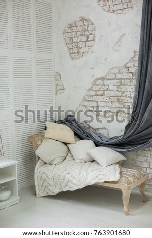 daybed with cushions in a corner of the room. wall of white brick in the room