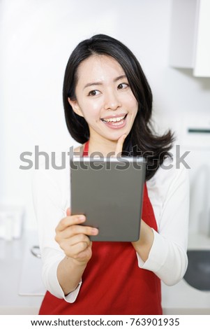 Beautiful young woman holding digital tablet in the kitchen.