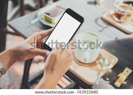 Woman relaxing while using smartphone blank screen for graphics display montage.Over the shoulder view of