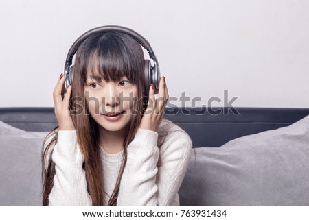 Beautiful Asian women who listen to music on the sofa are smiling