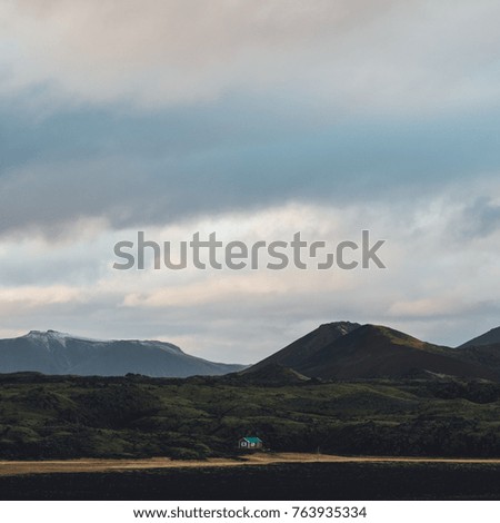 small hut with a grand backdrop of mountains and clouds in iceland