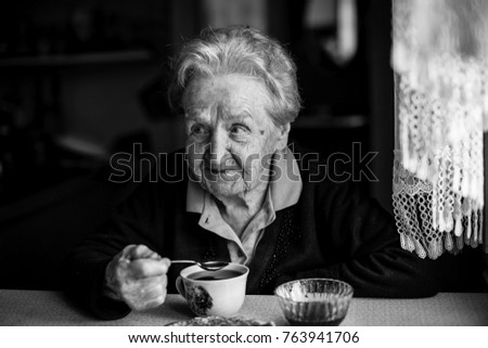 Elderly woman drinking tea, black and white portrait.