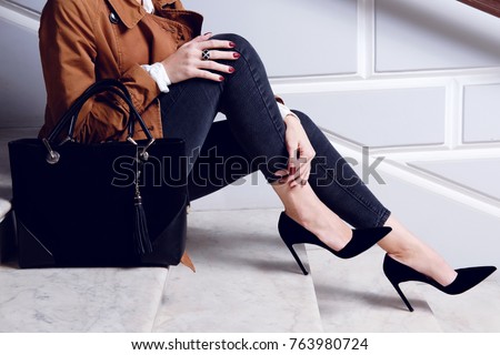 Closeup legs fashionable woman wear black high heels shoes and sitting on the white stairs. Stylish fall and spring outfit Royalty-Free Stock Photo #763980724
