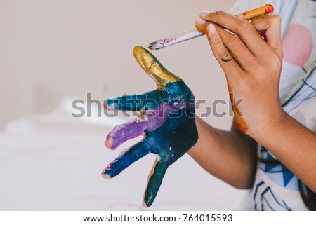 Education , Art and creativity learning concept - student painting her hands with colors