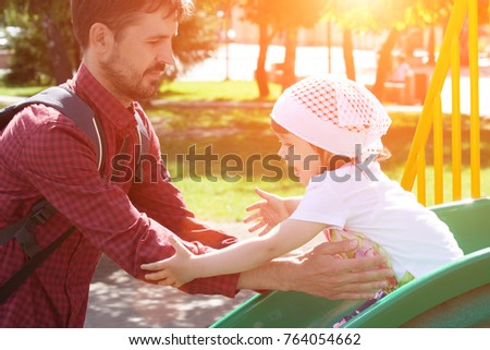 Dad plays with his daughter on the playground