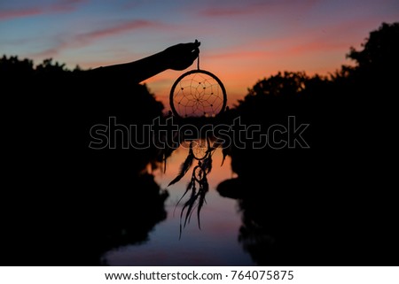 Hands holding a dreamcatcher sky background after sunset.