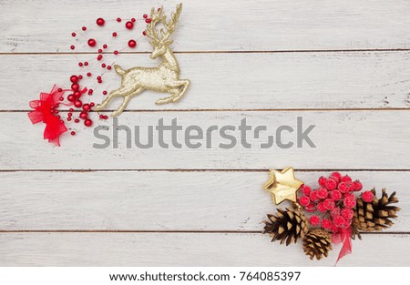 Christmas decoration - golden deer,red berries,cones and golden star on white wooden table ,greeting card, space for text
