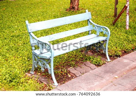 Relaxation concept : Long wood sticks in the garden : The classic green bench is placed on the sidewalk beside the lawn in the park.